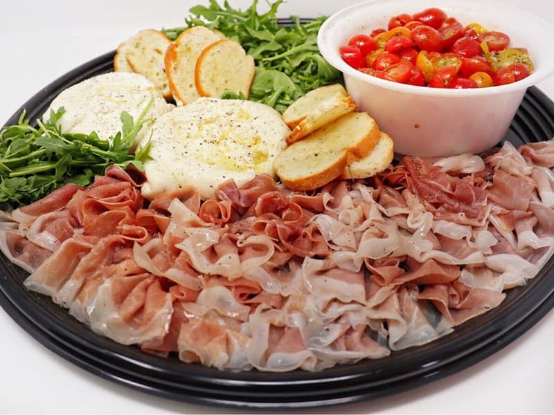 A burrata cheese platter with prosciutto and crostini
