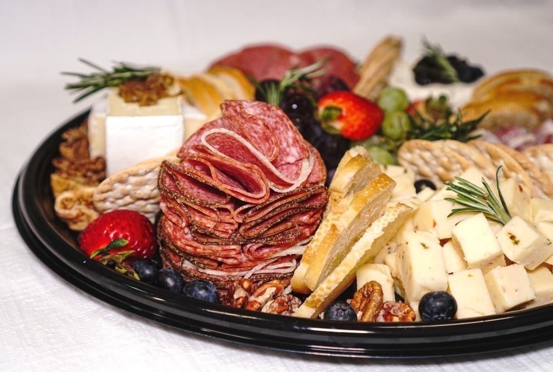 A cheese and charcuterie platter with crackers, grapes, and dried fruit