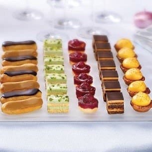 A row of petit fours: eclairs, layered squares, and macarons
